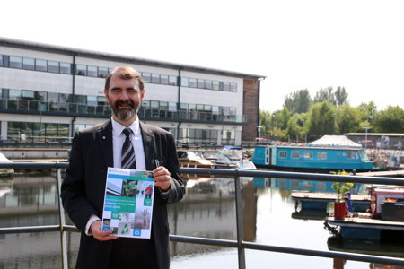 Councillor Low is pictured at Southbank Marina holding a copy of the Climate Action Plan.