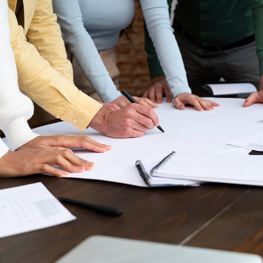 People gathered round a table with one person writing on a sheet of paper