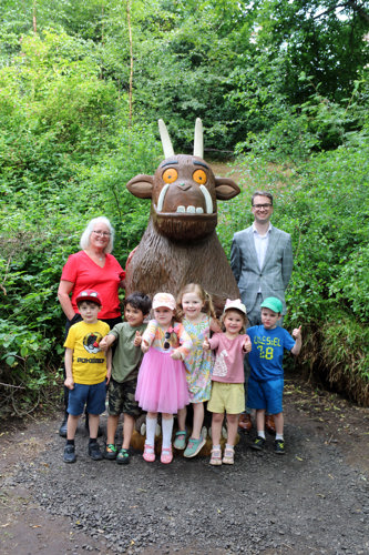 people standing next to a gruffalo statue