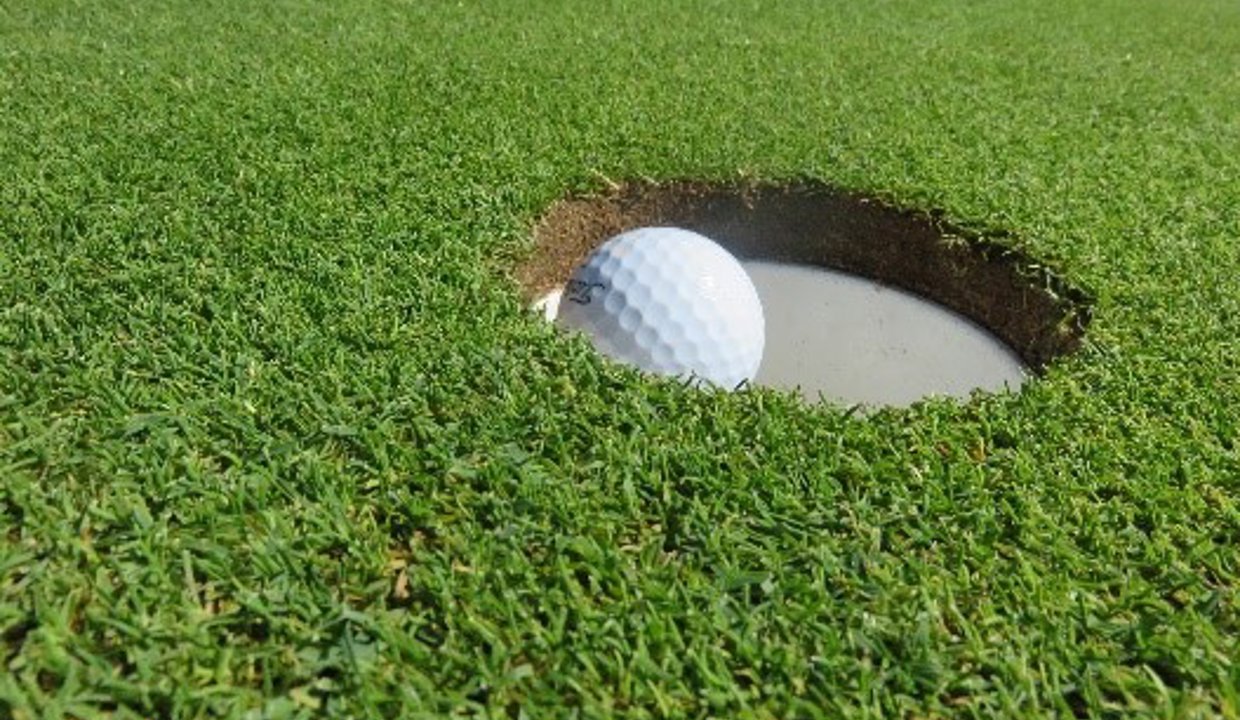 Golf ball falling into hole