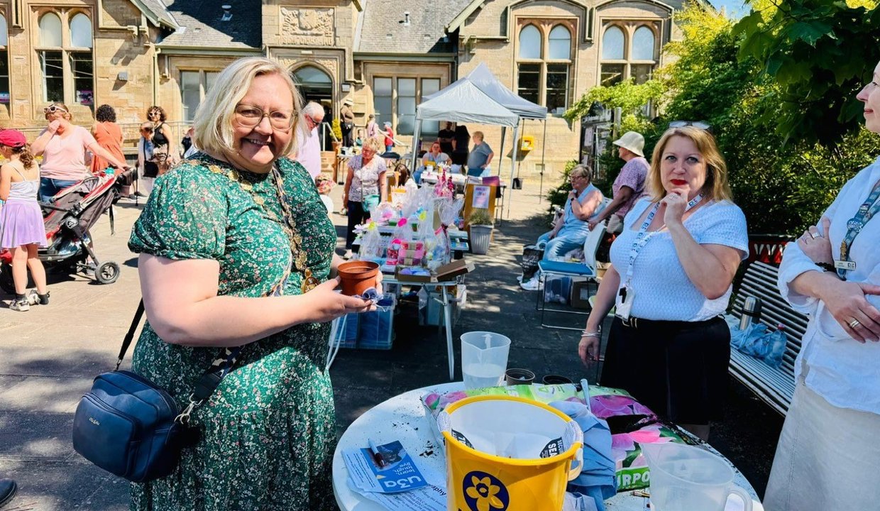 councillor renwick at one of the stall outside the library holding a plantpot