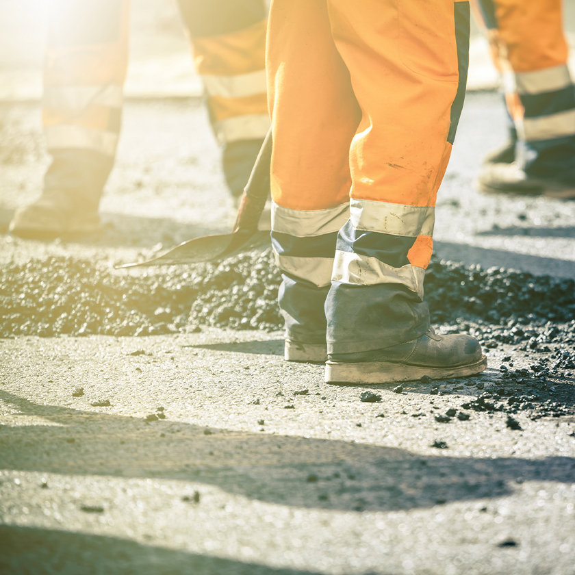 Construction workers wearing orange boiler suits doing work on the roads