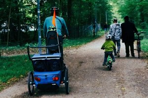 A photo of people cycling and walking in a forested area