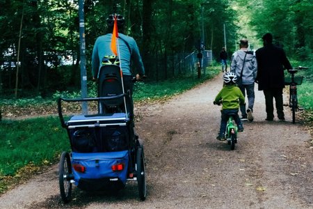 A photo of people cycling and walking in a forested area