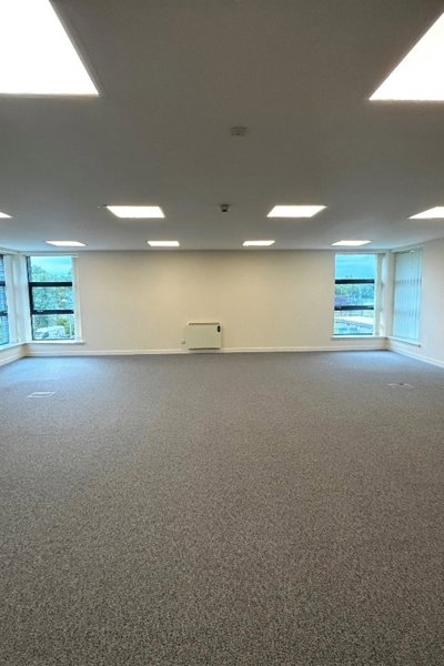 view of an empty room with grey carpet and windows at the far end