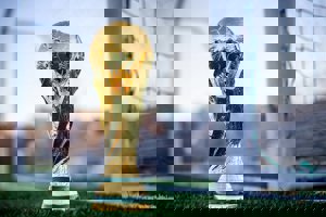 A photo of a World Cup replica trophy in front of football goals.