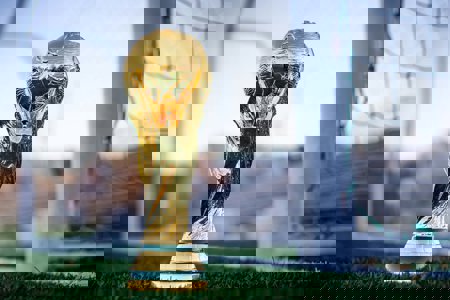 A photo of a World Cup replica trophy in front of football goals.