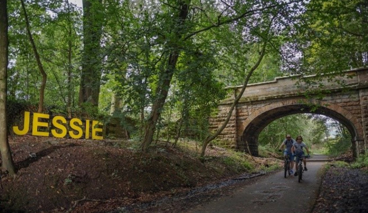 People cycling along the Strathkelvin Railway Path with a bridge in the background