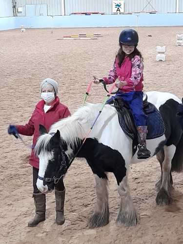 Girl on horse being led by coach